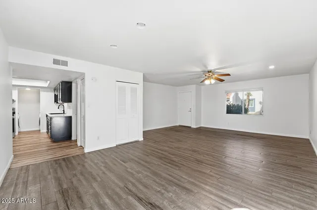a view of empty room with wooden floor and fan
