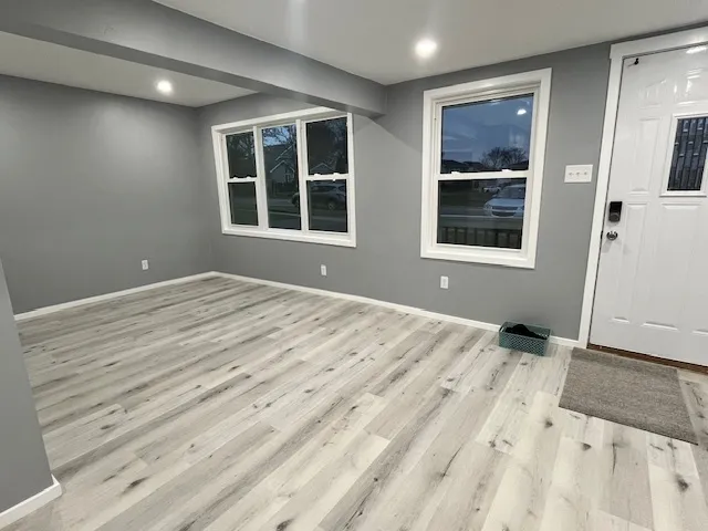 a view of an empty room with a window and wooden floor