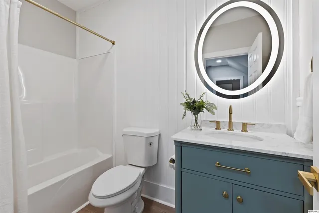 a bathroom with a granite countertop toilet a sink and a mirror