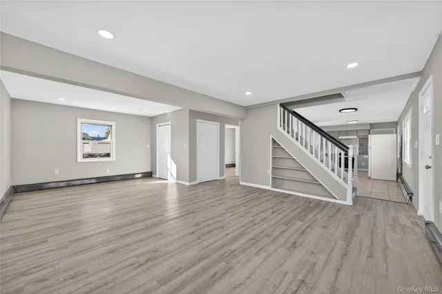 a view of an empty room with wooden floor and stairs