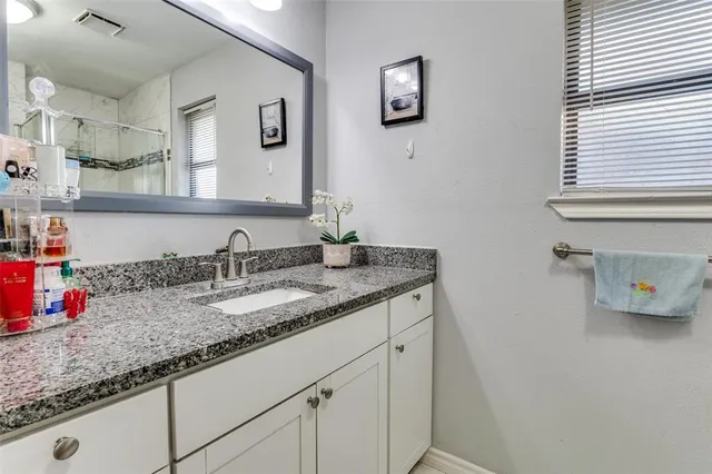 a bathroom with a granite countertop sink and a mirror