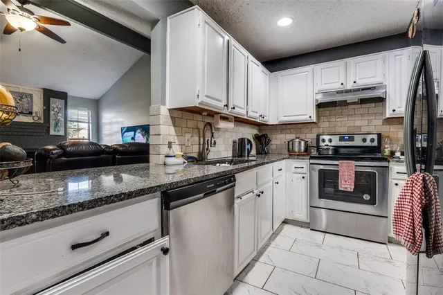 a kitchen with stainless steel appliances granite countertop a sink a stove and cabinets