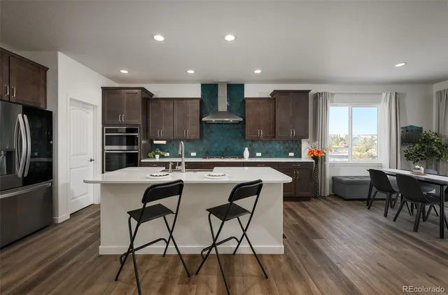 a kitchen with kitchen island granite countertop wooden floors and white stainless steel appliances