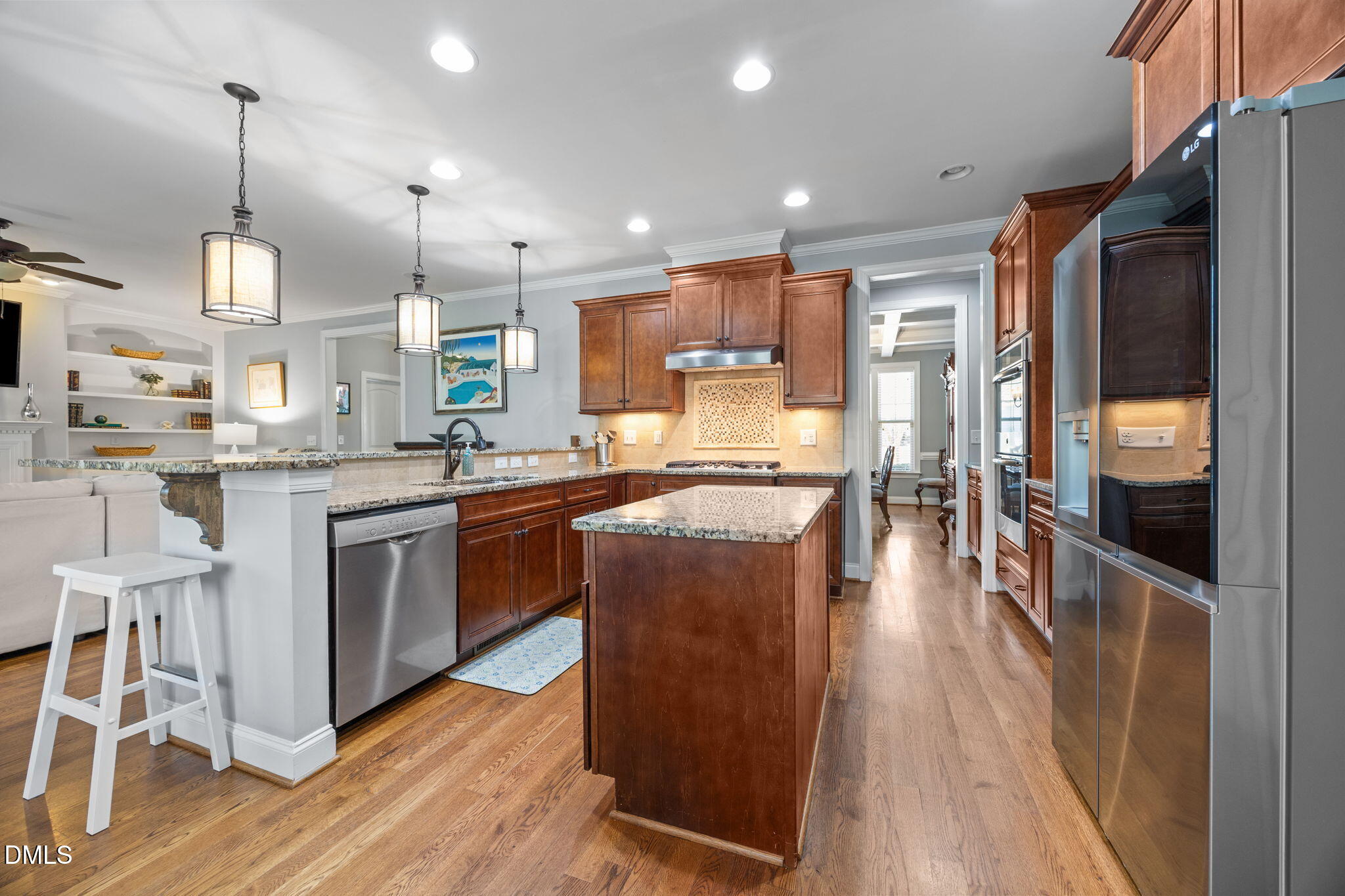 4603 Brighton Ridge Drive Apex, NC 27539 - Photo 20 of 69 a kitchen with stainless steel appliances kitchen island granite countertop wooden floors and view of living room