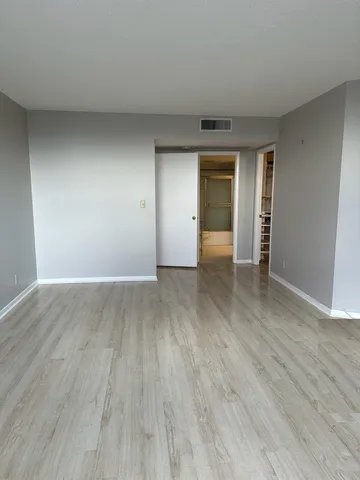 a view of an empty room with wooden floor and window