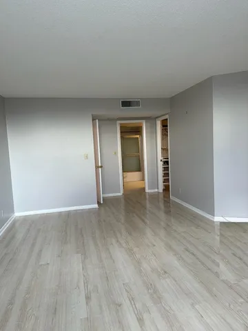 a view of an empty room with wooden floor and closet