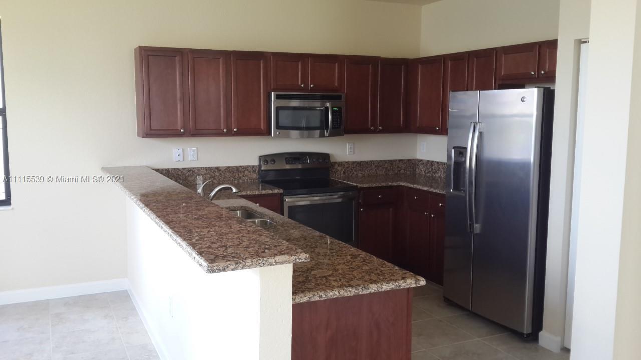 8630 West 33rd Avenue Hialeah, FL 33018 - Photo 2 of 22 a kitchen with granite countertop wooden cabinets and a stainless steel appliances