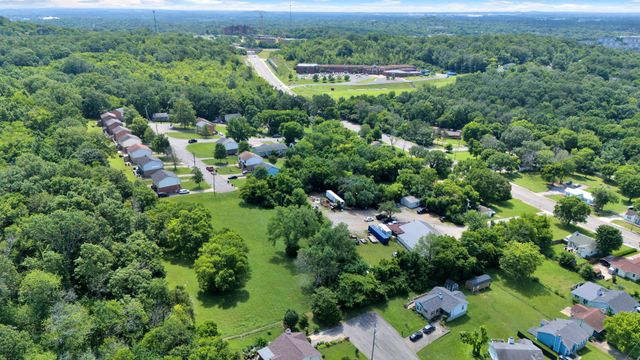 an aerial view of a residential houses with outdoor space and trees