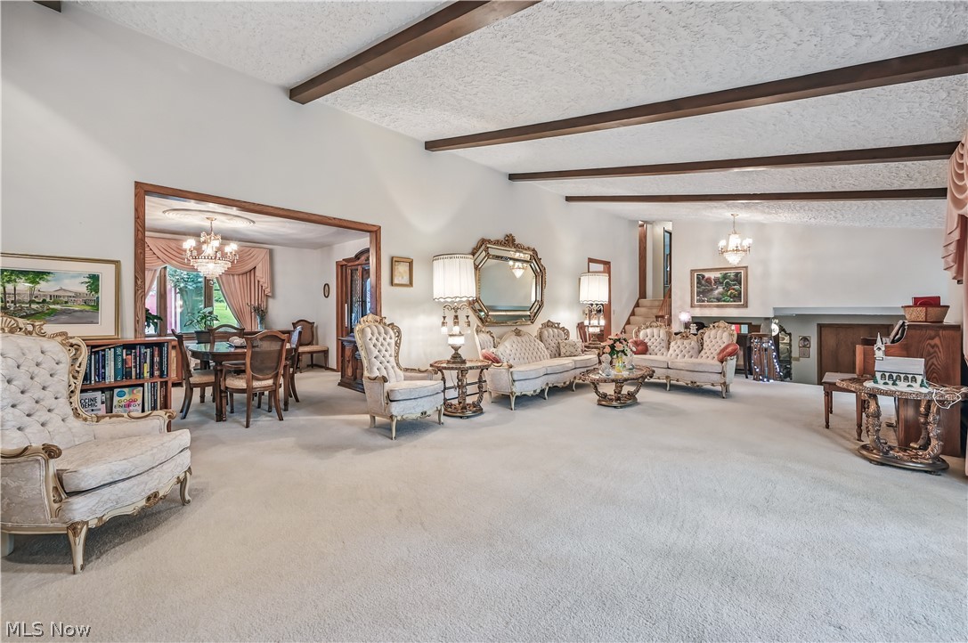 2717 Niles Vienna Road Niles, OH 44446 - Photo 8 of 50 Carpeted living room with a chandelier, beamed ceiling, and a textured ceiling