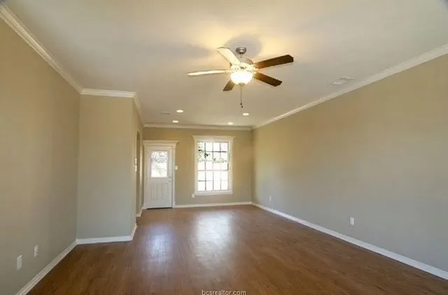 a view of empty room with wooden floor and fan