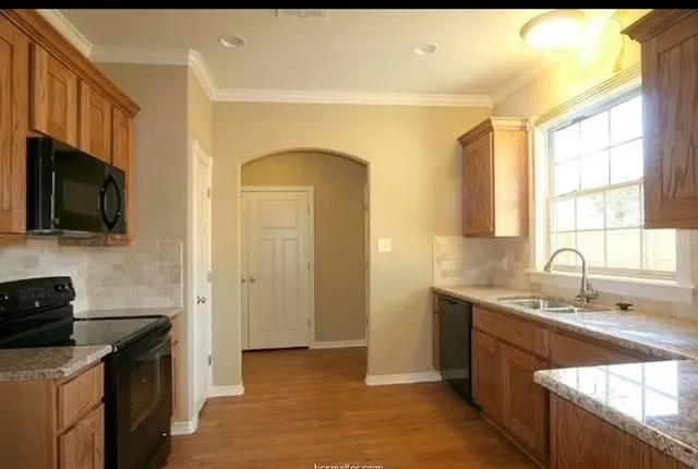 a kitchen with stainless steel appliances granite countertop a sink a stove and a refrigerator