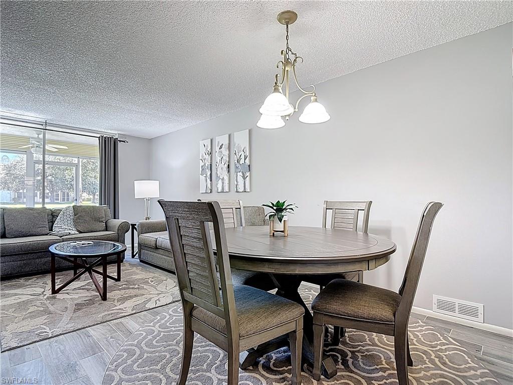 200 Turtle Lake Court, Unit 109 Naples, FL 34105 - Photo 12 of 37 Dining room with a textured ceiling, wood finished floors, and a chandelier