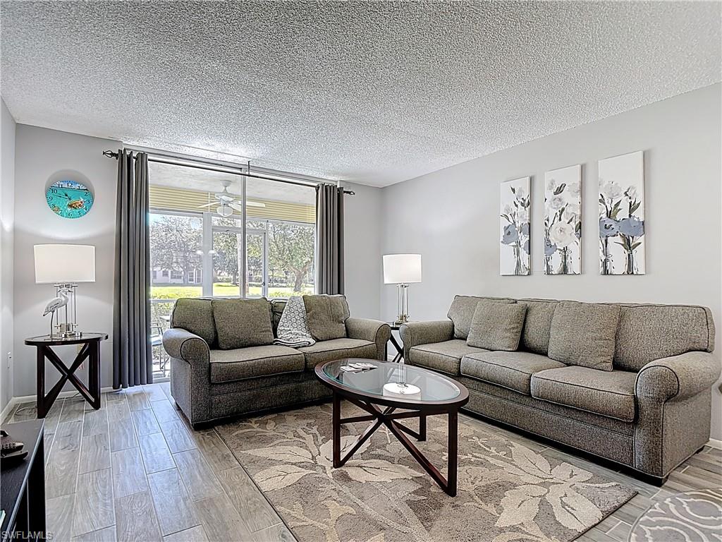 200 Turtle Lake Court, Unit 109 Naples, FL 34105 - Photo 16 of 37 Living room featuring light wood finished floors and a textured ceiling