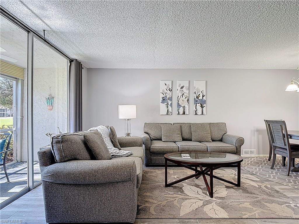 200 Turtle Lake Court, Unit 109 Naples, FL 34105 - Photo 17 of 37 Living area featuring a textured ceiling and wood finished floors