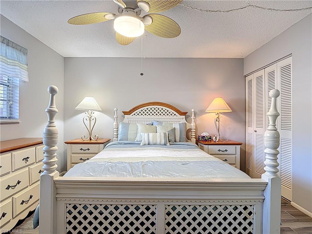 200 Turtle Lake Court, Unit 109 Naples, FL 34105 - Photo 22 of 37 Bedroom with dark wood finished floors, a textured ceiling, a ceiling fan, and a closet