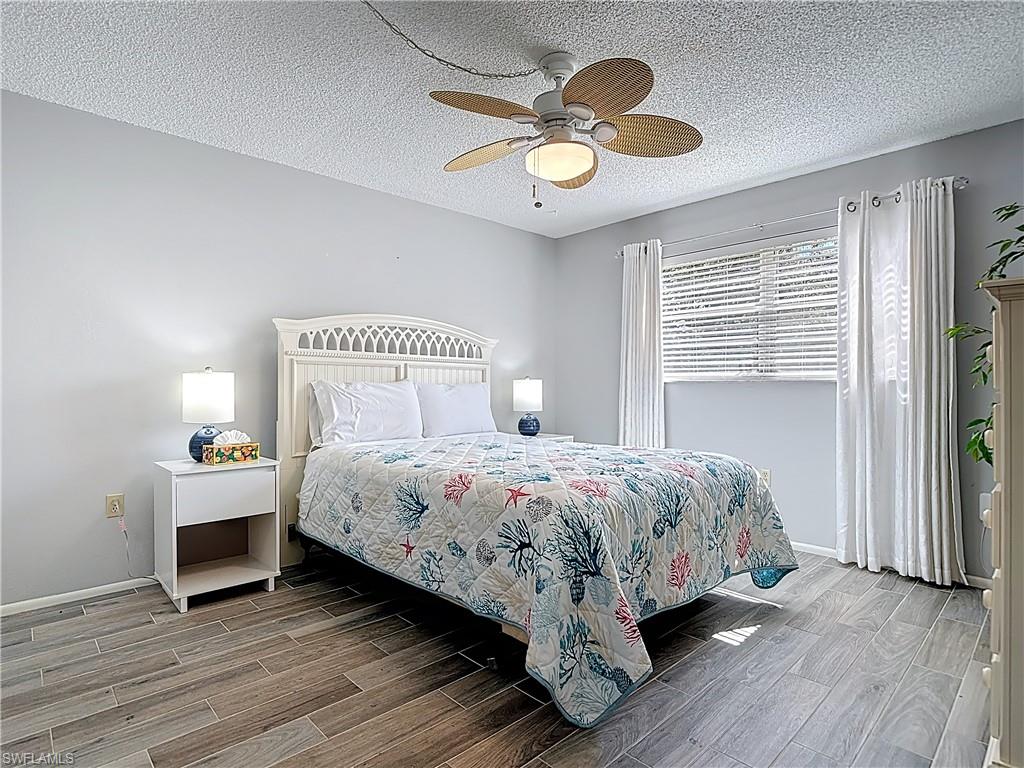 200 Turtle Lake Court, Unit 109 Naples, FL 34105 - Photo 27 of 37 Bedroom featuring wood tiled floors, a textured ceiling, and ceiling fan