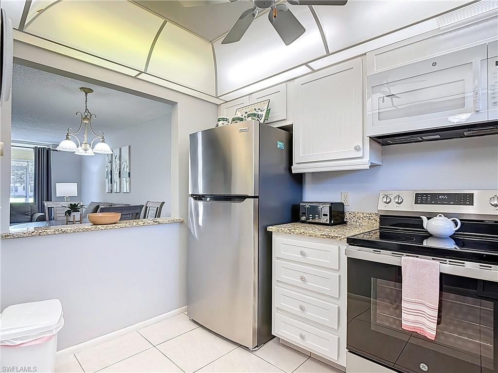 200 Turtle Lake Court, Unit 109 Naples, FL 34105 - Photo 6 of 37 Kitchen with appliances with stainless steel finishes, white cabinetry, light stone counters, and light tile patterned floors