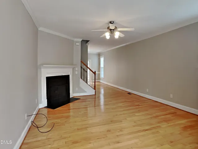 a view of empty room with wooden floor and ceiling fan