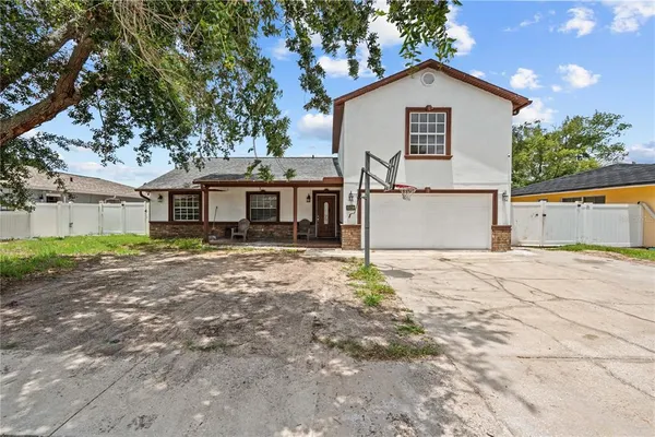 a view of a white house with a yard and large tree