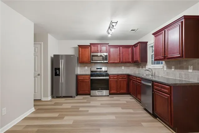 a kitchen with stainless steel appliances granite countertop wooden cabinets a sink and dishwasher a stove with wooden floor