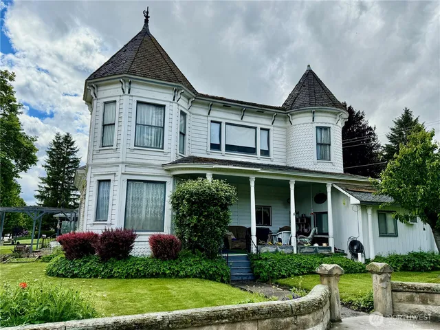 a front view of a house with a yard and potted plants