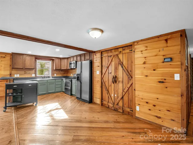 a view of a kitchen with kitchen island a sink wooden floor and stainless steel appliances