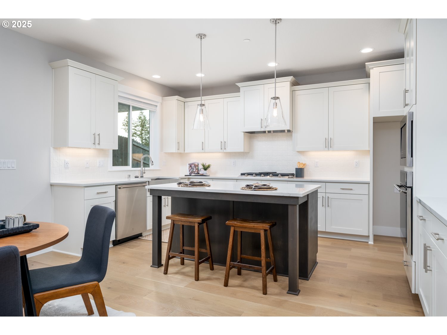 1392 North Kalani Loop, Unit LOT 57 Ridgefield, WA 98642 - Photo 16 of 47 a kitchen with a dining table chairs and white cabinets