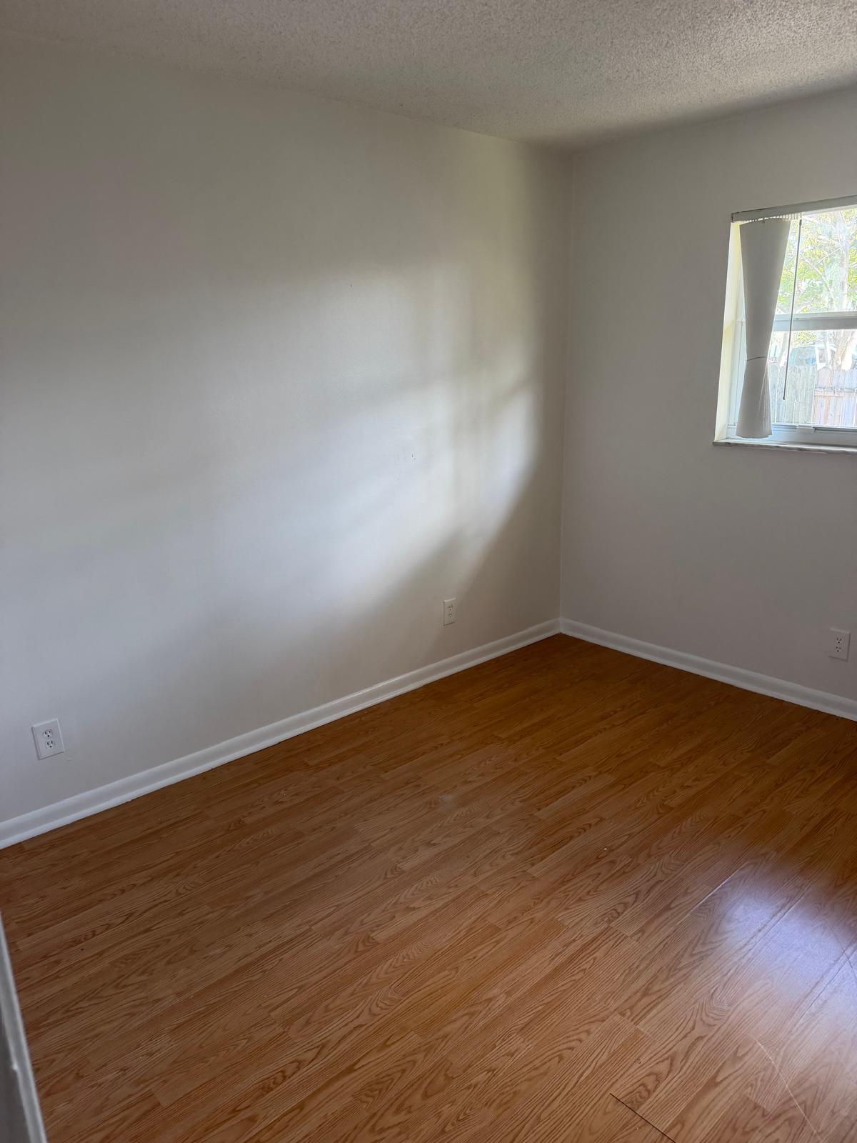 4429 Melvin Road, Unit A Lake Worth Beach, FL 33461 - Photo 11 of 20 a view of an empty room with wooden floor and a window