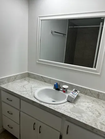a bathroom with a granite countertop sink and a toilet
