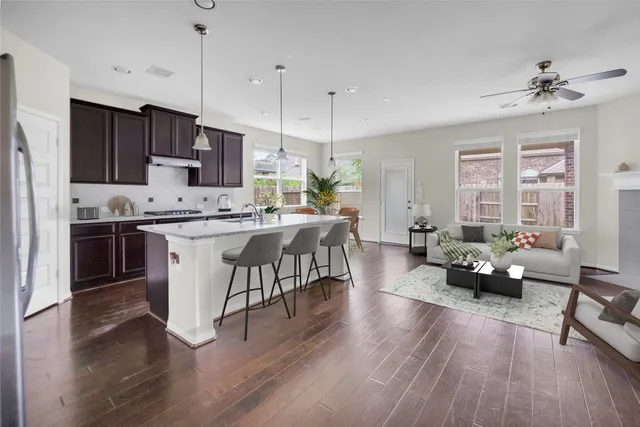 a living room with stainless steel appliances kitchen island granite countertop furniture a wooden floor and a chandelier