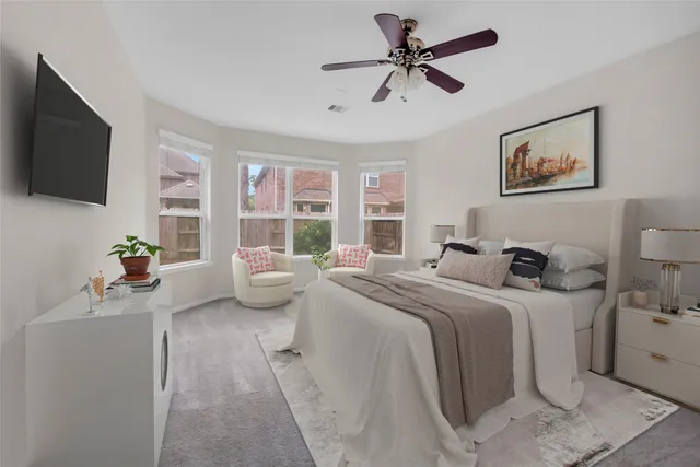 a bedroom with a bed a couch and a flat tv screen on dresser