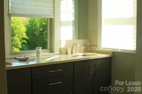 a bathroom with a granite countertop sink and a window