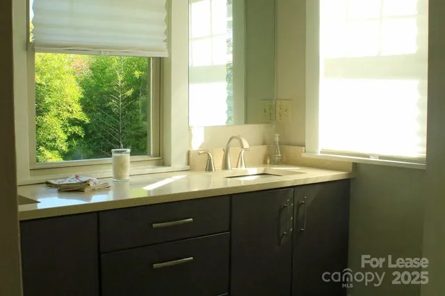 a bathroom with a granite countertop sink and a window