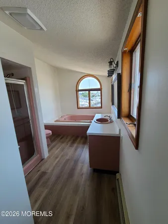 an empty room with wooden floor closet and windows