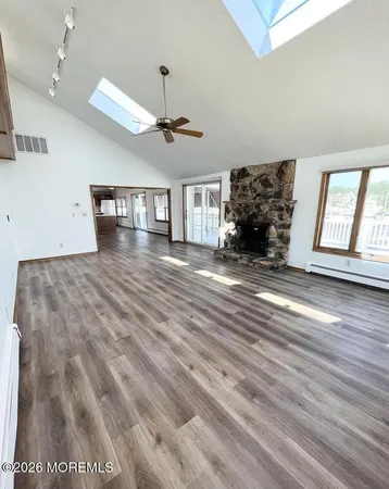 a view of an empty room with window and wooden floor