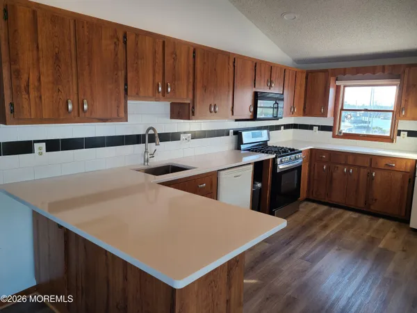 a kitchen with stainless steel appliances granite countertop a sink dishwasher stove top oven and cabinets with wooden floor
