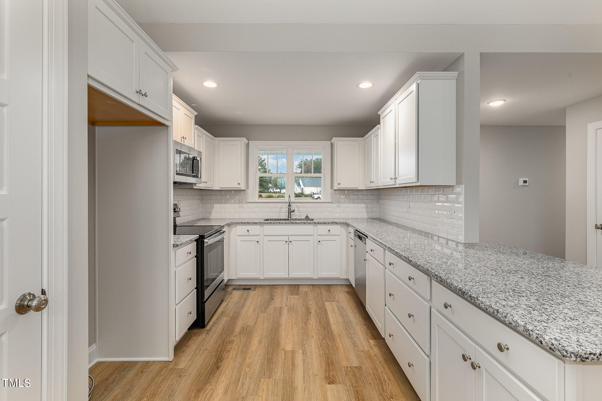 7882 Highway 27 Coats, NC 27521 - Photo 10 of 13 a kitchen with granite countertop white cabinets sink and stainless steel appliances