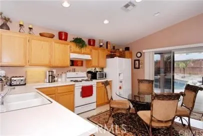 a kitchen with stainless steel appliances kitchen island granite countertop a sink a stove and a refrigerator