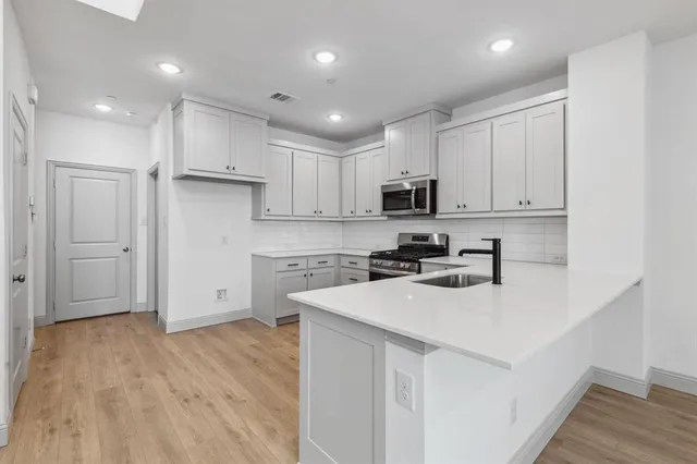 a kitchen with stainless steel appliances granite countertop a stove a sink and a microwave