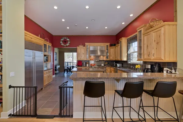 a kitchen with stainless steel appliances granite countertop a refrigerator a stove a sink dishwasher and chairs with wooden floor