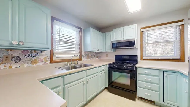 a kitchen with a sink cabinets appliances and a window