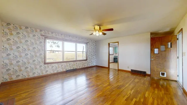 a view of an empty room with a window and wooden floor