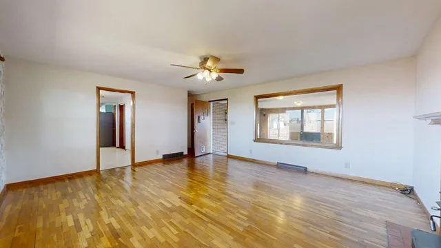 a view of an empty room with window and wooden floor