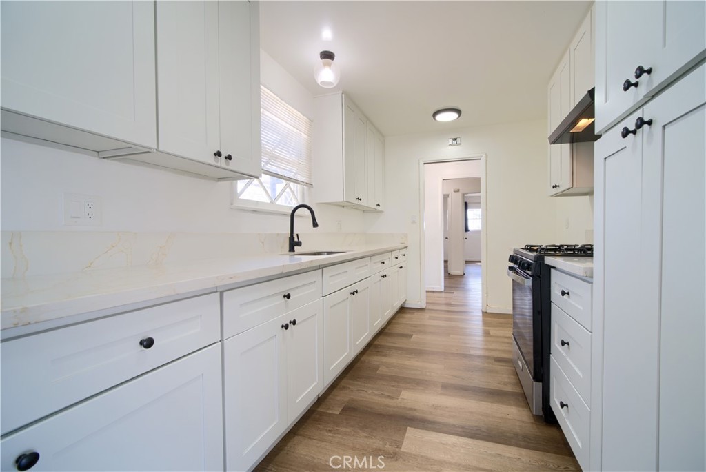6083 Merito Avenue San Bernardino, CA 92404 - Photo 5 of 17 a large white kitchen with a sink and wooden floor