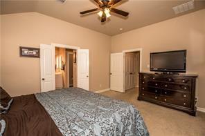 1409 Rosson Road Little Elm, TX 75068 - Photo 22 of 34 Vaulted ceiling bedroom with a ceiling fan, carpet flooring, a white interior door, and an additional open doorway revealing a vanity with dual mirrors