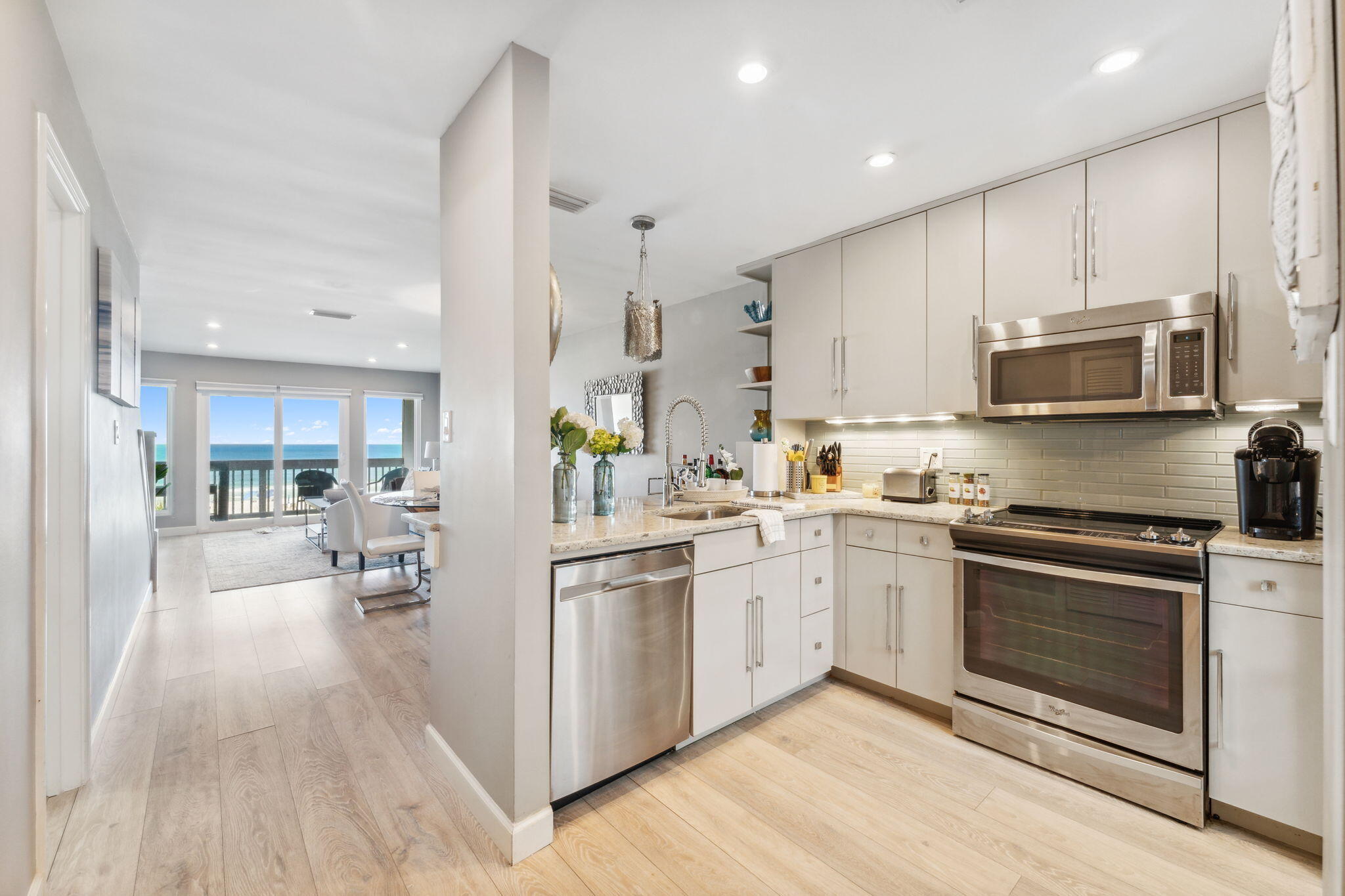 a kitchen with stainless steel appliances granite countertop a stove top oven a sink dishwasher and a refrigerator with wooden floor