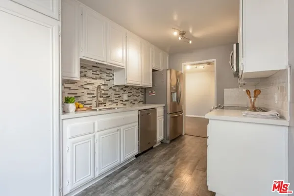 a kitchen with stainless steel appliances granite countertop a sink and a white cabinets
