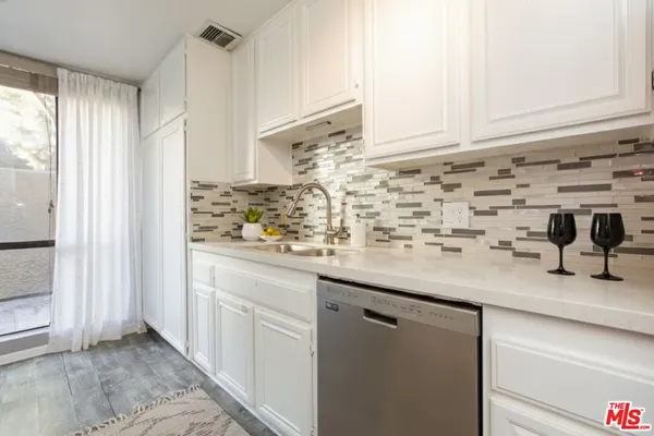 a kitchen with stainless steel appliances granite countertop white cabinets and a stove top oven
