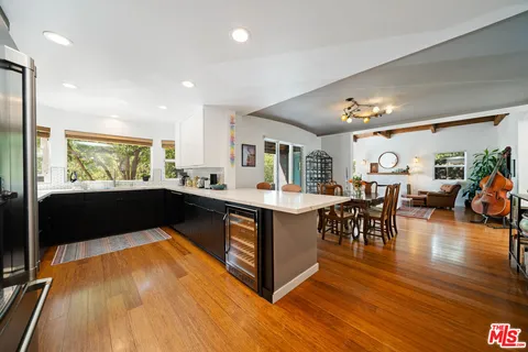 a kitchen with stainless steel appliances a sink dishwasher a stove top oven a refrigerator with wooden cabinets and floor