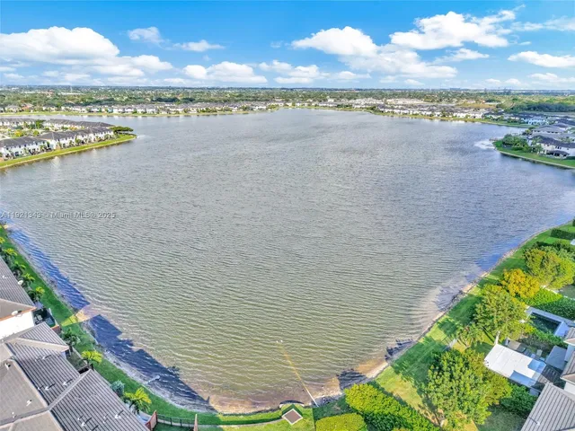 a view of a dining room and livingroom with furniture wooden floor a rug a painting and a chandelier